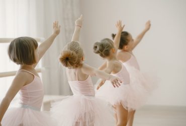 Cute little ballerinas in pink ballet costume. Children in a pointe shoes is dancing in the room. Kid in dance class.